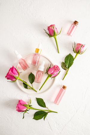 Natural organic facial skin care product based on rose petal oil in cosmetic bottles on a white textured background. Top view. Vertical view.の写真素材