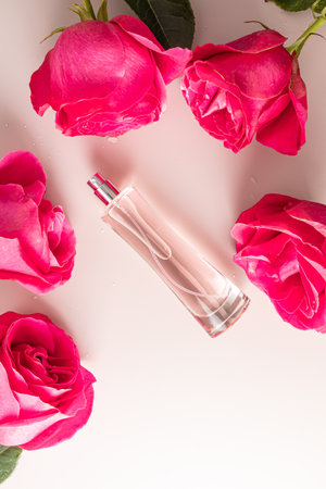Vertical top view of an elegant bottle of cosmetic spray or eau de parfum with the scent of delicate roses among roses. A copy spaceの写真素材