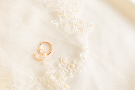 Two gold wedding rings lie on the bride's embroidered tulle with soft pleats. beautiful wedding background. layout for design. A postcardの写真素材