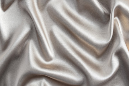 Abstract satin silver background of luxurious fabric. soft gentle waves of fabric. The golden texture of the fabric. Festive, New Year's background.の写真素材
