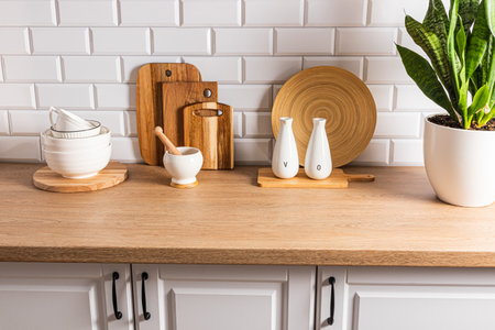 Beautiful kitchen background with different items and kitchen utensils made of eco-friendly materials. wooden countertop, white brick wallの写真素材