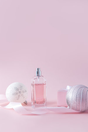 Chic bottle of women's perfume or spray among beautiful Christmas balls and ribbon. Vertical view. copy of space. Product presentationの写真素材