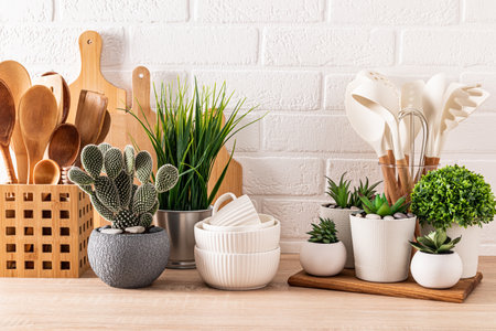 set different kitchen utensils and set of different green potted plants on a wooden kitchen countertop in an eco-friendly kitchen. Front viewの写真素材
