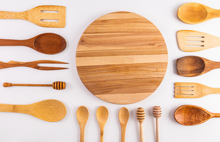 Beautiful kitchen background with wooden tool on a white table with a round cutting board in the center. Flat lay. Top view. space for textの写真素材