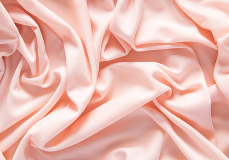 Elegant satin fabric with a peachy color. luxurious texture of the soft folds. festive background. design. color of the year peachy fuzzの写真素材