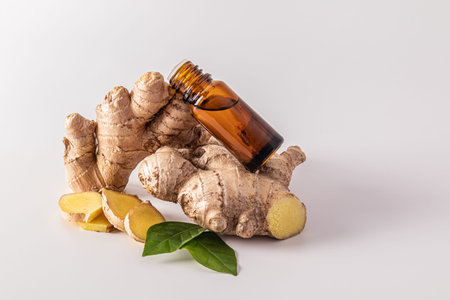 An amber glass bottle with a dropper with a natural remedy or ginger oil lies on the ginger root....