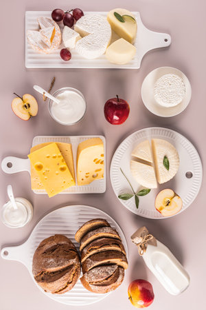 Fresh dairy products, bread, cheese, cottage cheese, sour cream on different white boards. Top vertical view. Flat lay. The concept of of Shavuot.の写真素材