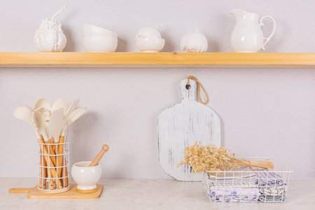 Bright kitchen space in a modern kitchen. Towels in a metal basket, a set of kitchen tools. Decorative pumpkins on an open wooden shelf. Front viewの写真素材