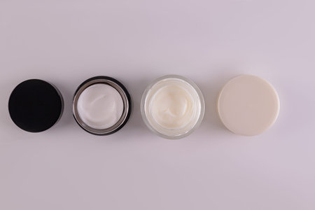A set of glass jars with cosmetic cream of different colors for face and body skin care. Design....