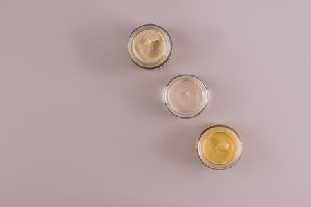 A set of glass jars with cosmetic cream of different colors for face and body skin care. Design. packaging. Product presentation. Top view. mockup.の写真素材