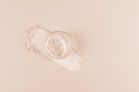 The jar of light loose powder in the jar sits on the powder swatch next to the makeup pad. Top view. Delicate matte powder. Easy blendingの写真素材
