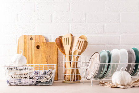 A set of ceramic plates in the dryer, wooden cooking tools, cutting boards, many different towels in the storage area. Trendy eco style in kitchen.の写真素材