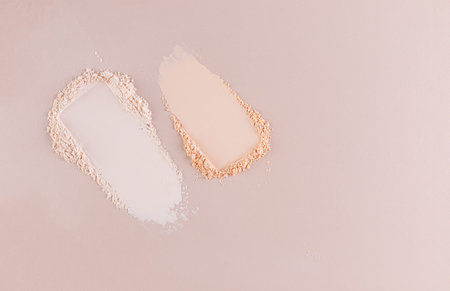 Two samples of loose face makeup powder in beige and natural tone on a pastel background. top view....