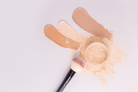 Different samples of foundation powder, a cosmetic jar with loose powder of a natural tone, a chic large brush for applying makeup. top viewの写真素材