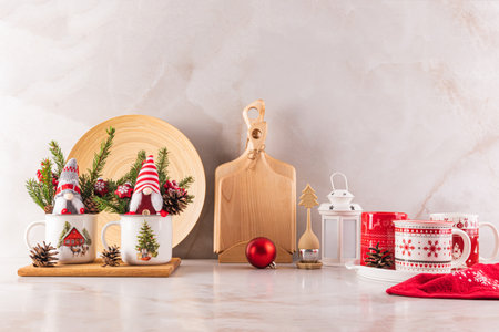 Two New Year's gnomes in mugs and spruce branches on the kitchen countertop with wooden eco utensils. Christmas mood in the kitchen spaceの写真素材