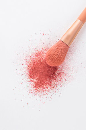 A beautiful makeup brush is lying on a sample of dry scattered blush in a pink tone on white background. The top vertical view. decorative cosmetics.の写真素材