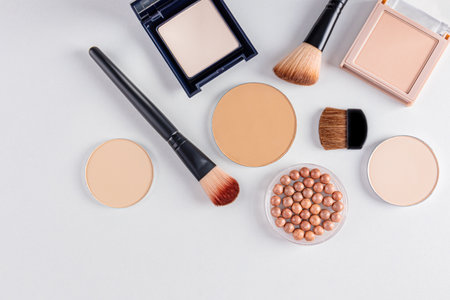 a set of cosmetic decorative makeup products in various packages and several brushes for applying makeup. white background. top view. beauty conceptの写真素材