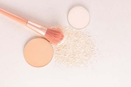 A sample of a round block of compact powder in a brown tone, a chic brush for applying makeup. loose beige powder sample. top view. layout for design.の写真素材