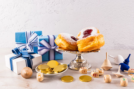 many holiday boxes, wooden dreidels, gold coins, donuts in a silver vase against a gray textured wall. Front view. The concept of Hanukkahの写真素材