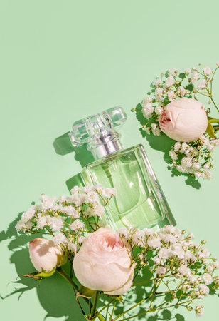 An elegant bottle of women's perfume with a light floral fragrance on a green delicate background with flowers. The top vertical view. A copy spaceの写真素材