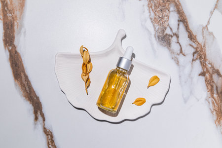 A clear bottle with a natural cosmetic product for face skin care panthenol, gold 24k on tray in the form of a shell. abstract marble. top viewの写真素材