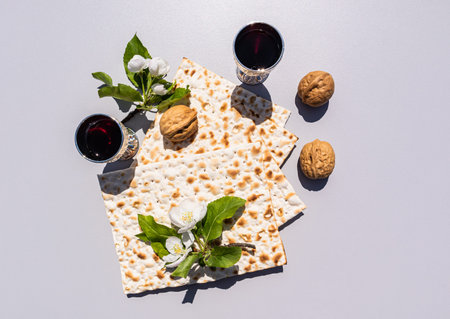 Festive composition of the Passover holiday. matzah, silver glasses with red wine, walnuts on a light background with twigs of blossoming apple treesの写真素材