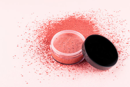 An open transparent cosmetic jar of pink-tone dry blush stands on a loose pink blush swatch. white background. A copy space. texture sampleの写真素材