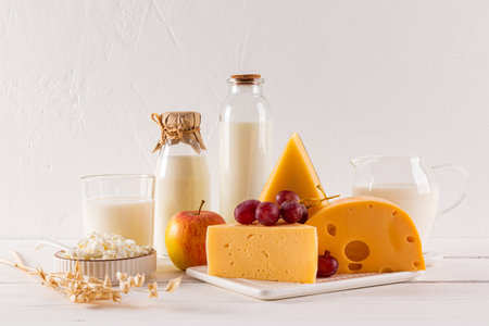Different varieties of cheese, bottles, glass, jug of milk on a white background. Traditional products of the Shavuot holiday. Front viewの写真素材