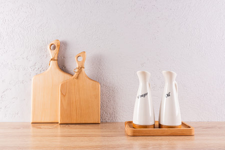 Kitchen background in a minimalist style. two cutting wooden boards and two ceramic special bottles of oil on a tray. Relief wall. Front viewの写真素材