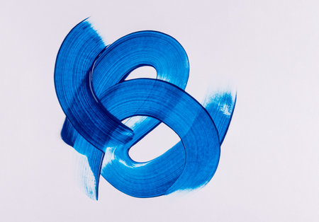 Beautiful curved lines of strokes in blue acrylic paint on a white background. elements of an artistic pattern. The concept of drawing with paint.の写真素材