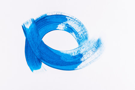 Beautiful curved lines of strokes in blue acrylic paint on a white background. The concept of drawing with paint. background in minimalism of styleの写真素材