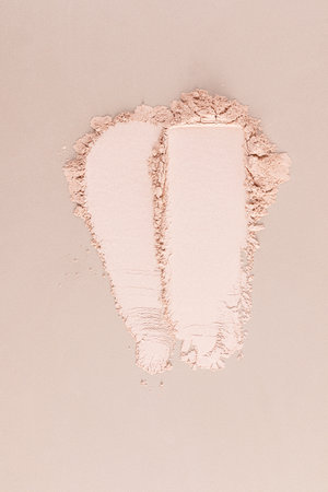 Two chic cosmetic samples of loose powder in a natural tone on a beige background. vertical top view. cosmetic texture. Layout for product advertising.の写真素材