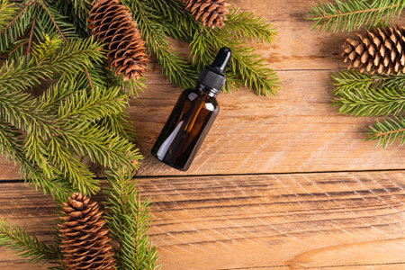 Cosmetic bottle with a natural product for the skin of the face, body, hair based on coniferous oil among spruce branches, cones. Top view. copy space.の写真素材