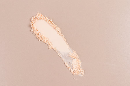 A beautiful sample texture of a dry compact powder in a natural tone on a beige background. top view. A copy space. layout product for advertising.の写真素材