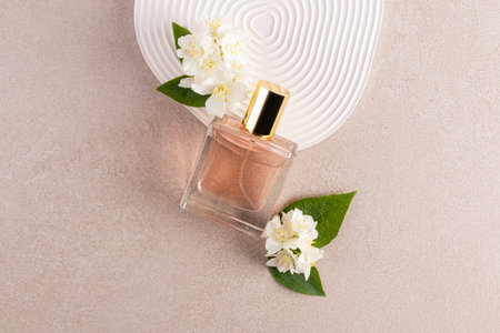 A glass bottle of jasmine-scented women's perfume is leaning on a relief podium with fresh jasmine flowers. A blank bottle mockup. A copy spaceの写真素材