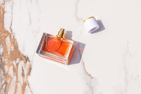 A chic bottle of cosmetic perfume or spray lies on an abstract marble background with a beautiful perfume cap. top view. A blank bottle mockup.の写真素材