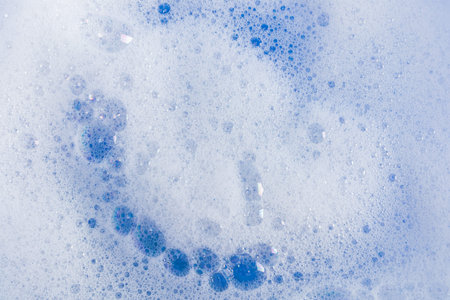 bubbles of detergent foam on blue water. the texture of a soapy cosmetic product. Abstract texture...