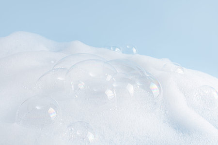 Chic white fluffy foam, soap foam texture with clear bubbles on blue background. A copy space. Layout for advertising detergent, spa cosmeticsの写真素材