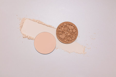 Two block of compact powder in different tones broken into pieces stands on sample texture powder. A sample texture. top view. Decorative cosmetics.の写真素材