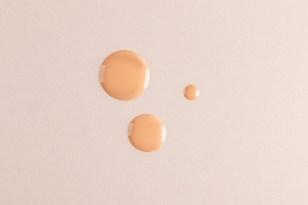 Three beautiful round drops of foundation on a beige background. top view. A copy of the space. Cosmetic texture sample. layout. templateの写真素材