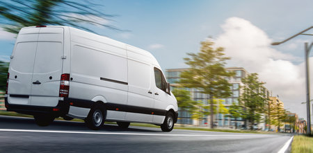 White commercial delivery van on the road. Side view. Blurred background.の写真素材