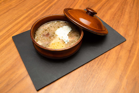 Food photography - Sour rye soup with egg, sausage and potatoes in a brown ceramic bowl -...