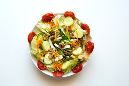 Dish of mix Italian salad with tomatoes, cucumbers, carrots, lettuce, feta, walnutsの写真素材