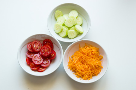 Dishes of red Italian tomatoes, orange carrots, green cucumbers for saladの写真素材