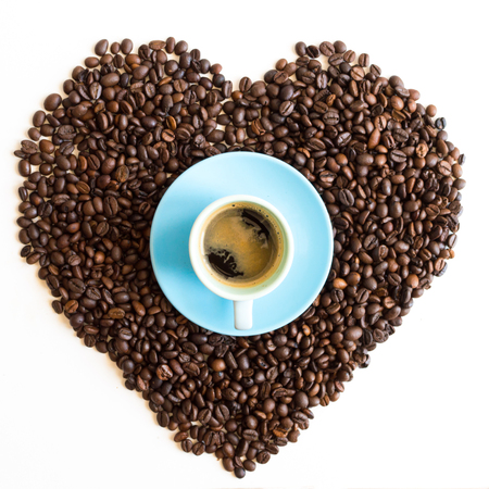 Heart of coffee beans with azure blue cup isolated on white backgroundの写真素材