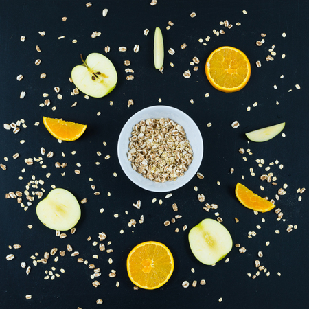Good morning with healthy breakfast with composition flat lay of sliced apple and orange, oats and whole spelled isolated on blackboard background - top viewの写真素材