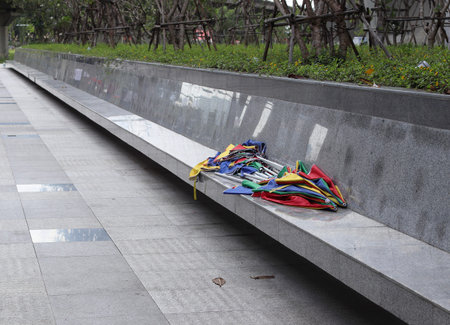 Pile of multicolors abandoned Broken umbrella thrown away and laying on the wall seat.