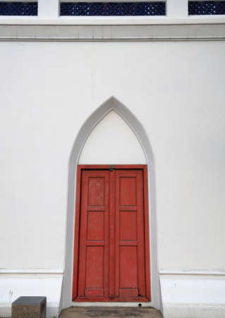 Old red wooden small door on the white ancient palace wallの写真素材