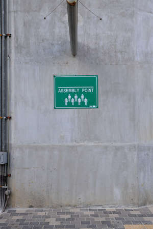 assembly point sign board on concrete wallの写真素材