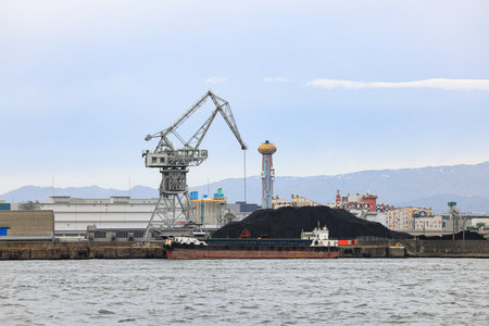 Large crane works on large coal stockpile at Osaka port.の写真素材